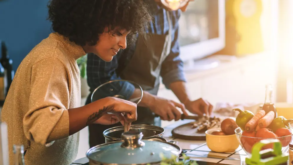 A woman tends a saucepan on a stove