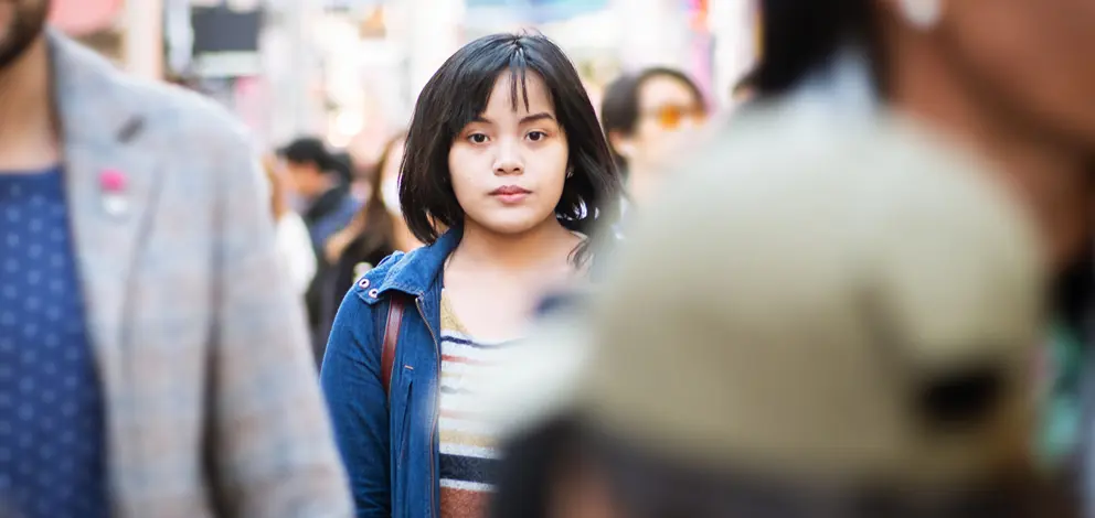 Girl in a crowd staring into the camera