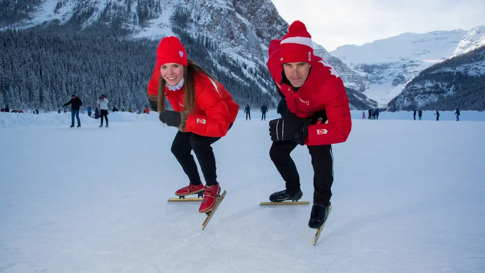 Josie and Denny on an outdoor ice rink surrounded by mountains