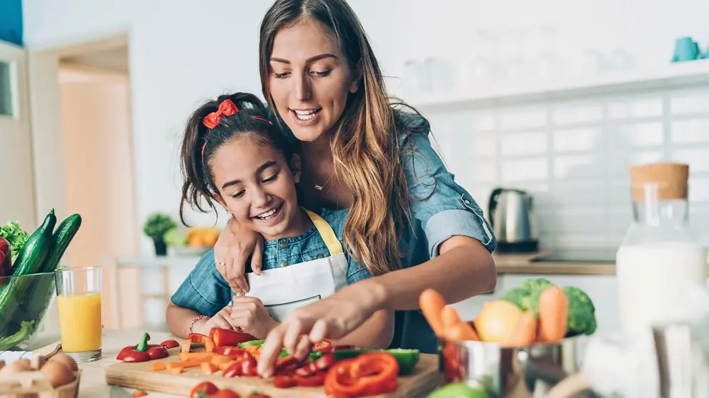 A little girl and her mom cook together.