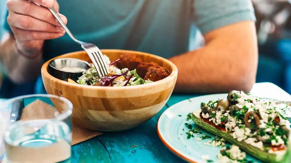 A man eats a salad from a bowl