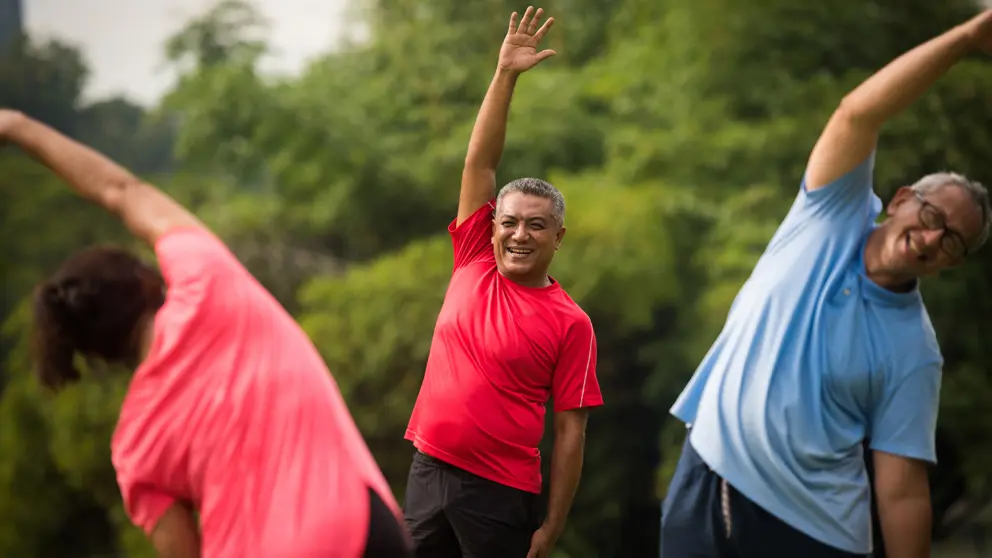 A group of active seniors enjoy a stretch session with their instructor in the park in the city