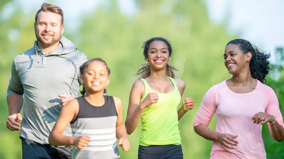 A family of four jogging, with two kids in the center and their parents on either side.