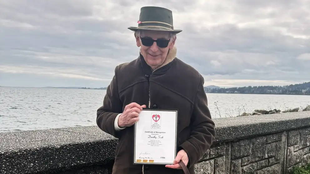 Heart & Stroke legacy donor Ken Scott holding a plaque awarded to his mother contributing to Heart & Stroke as a canvasser.