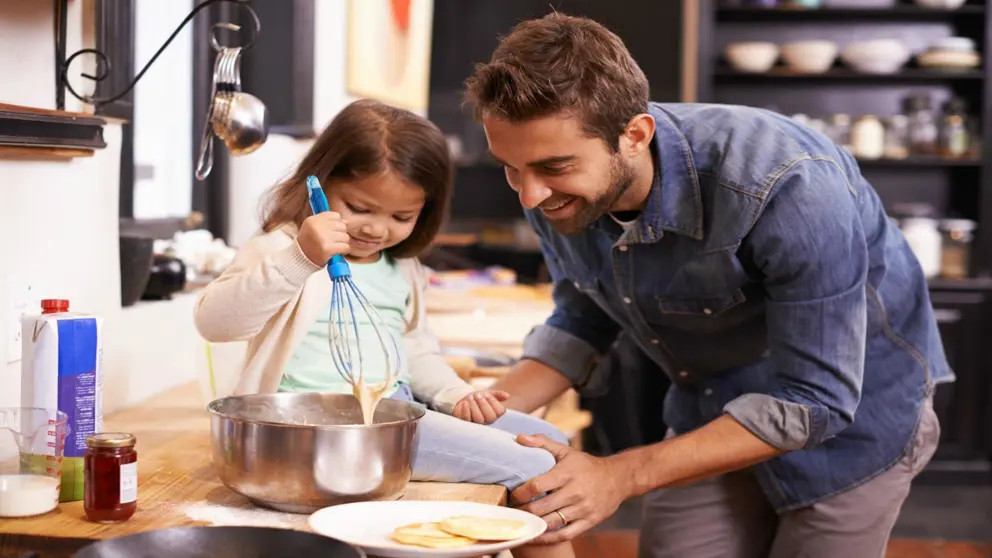 Father and daughter making pancakes in the kitchen 