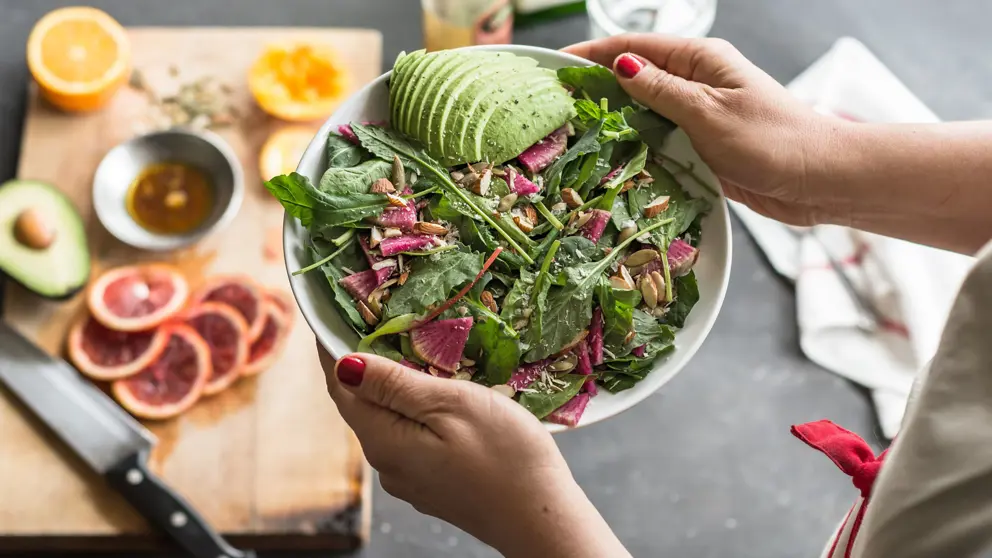 Woman holding fresh mixed green salad