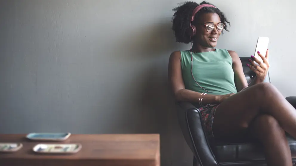 Woman relaxing in chair while listening to music on iPod