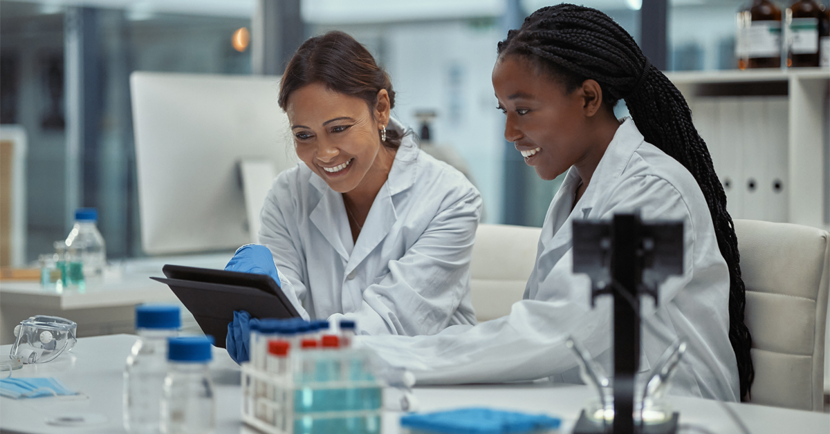 Two women in lab coats examining their research