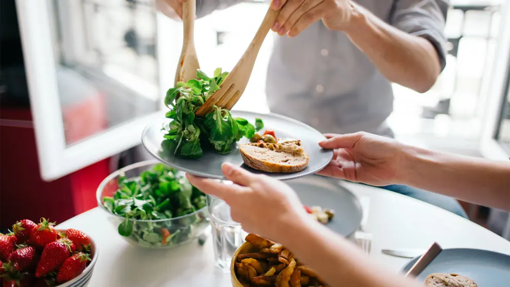 A person serving a vegetable salad