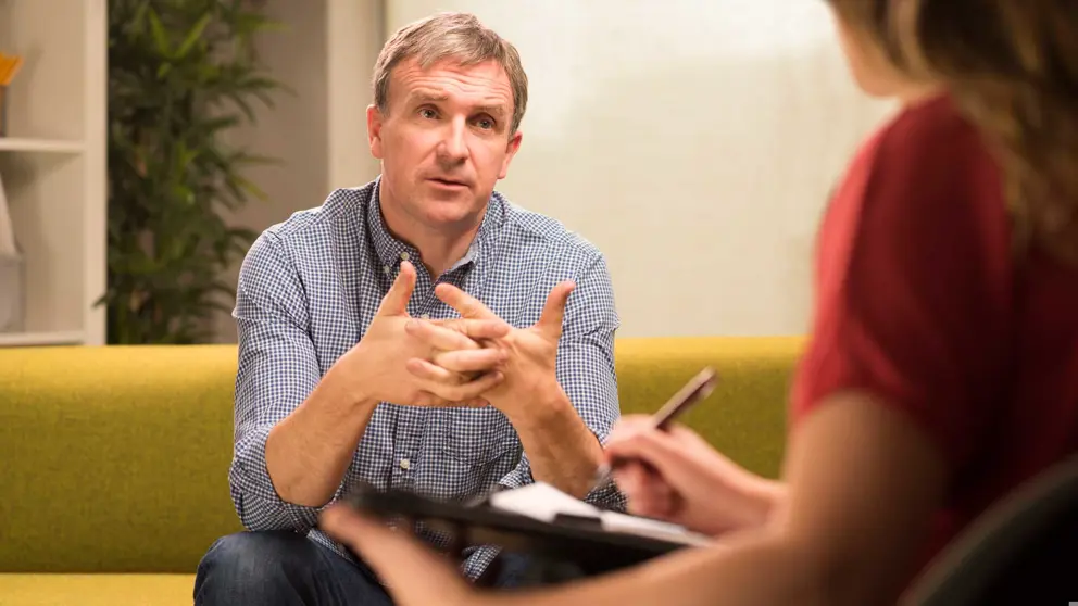 Man sitting on couch speaking to therapist