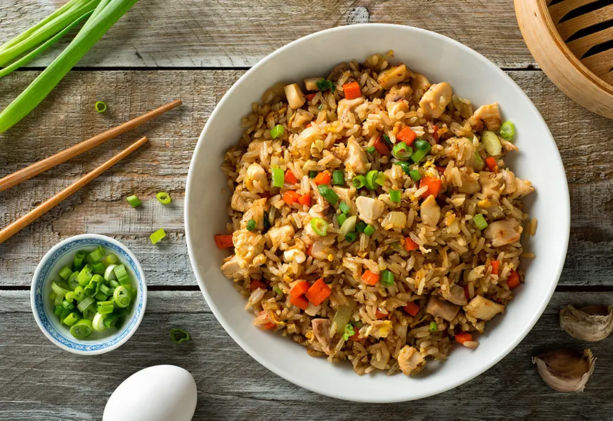 A bowl of chicken fried rice on a table