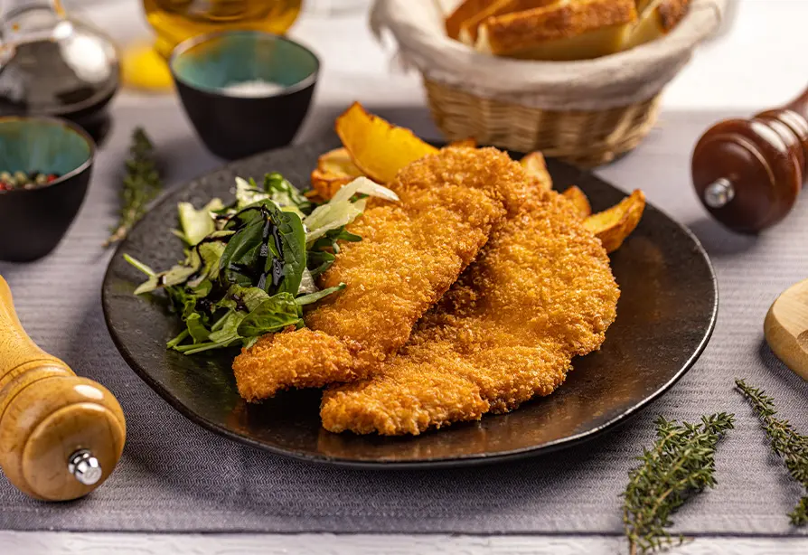 Breaded turkey fingers on a plate with vegetables