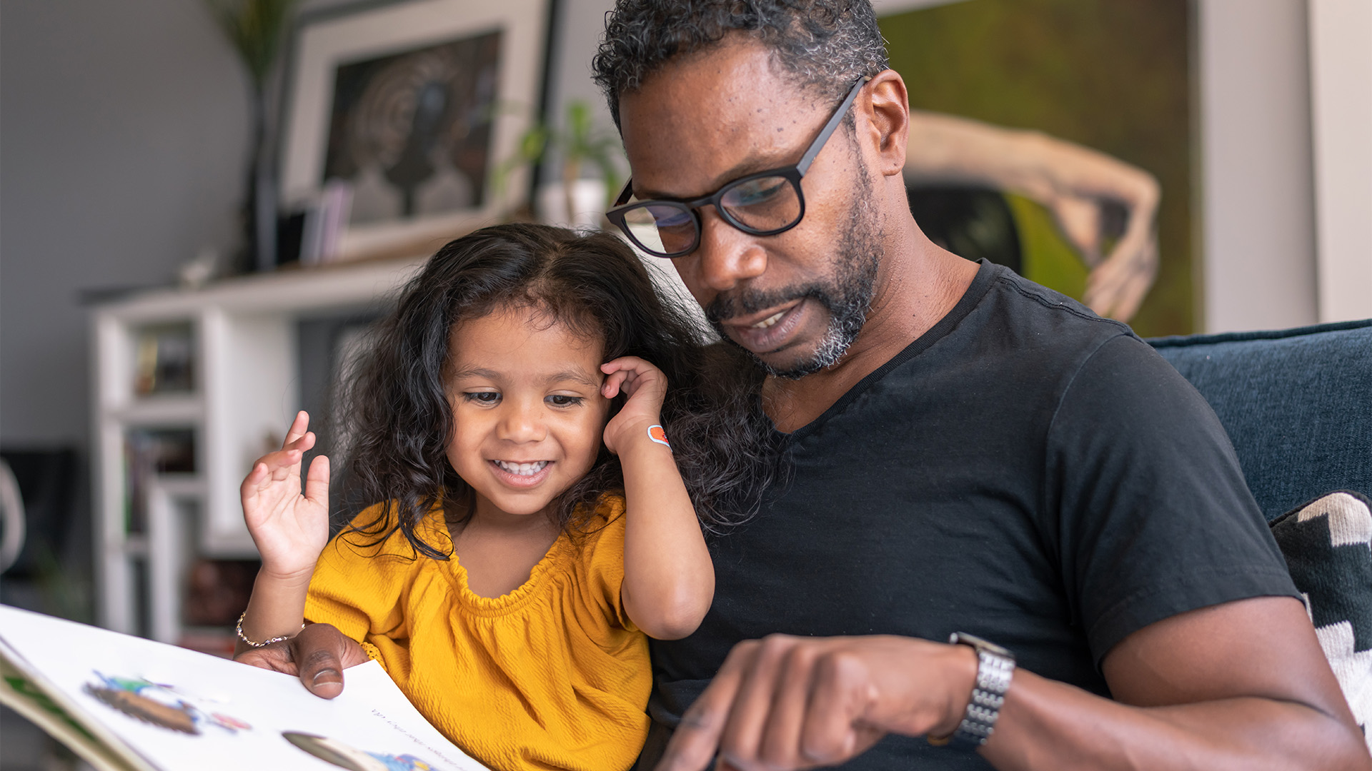 A father reading a picture book to his daughter