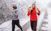 A couple running along a snowy winter road