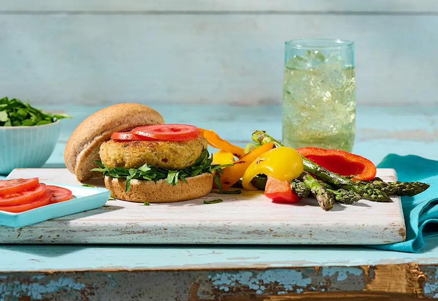 Salmon and quinoa patty served on a whole wheat bun, placed on a wooden board