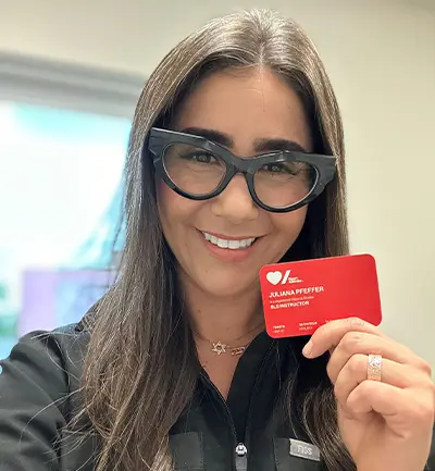 Julie Pfeffer holding her Heart & Stroke BLS instructor-certification card.