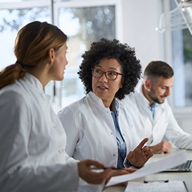 A group of medical professionals talking at their desk.