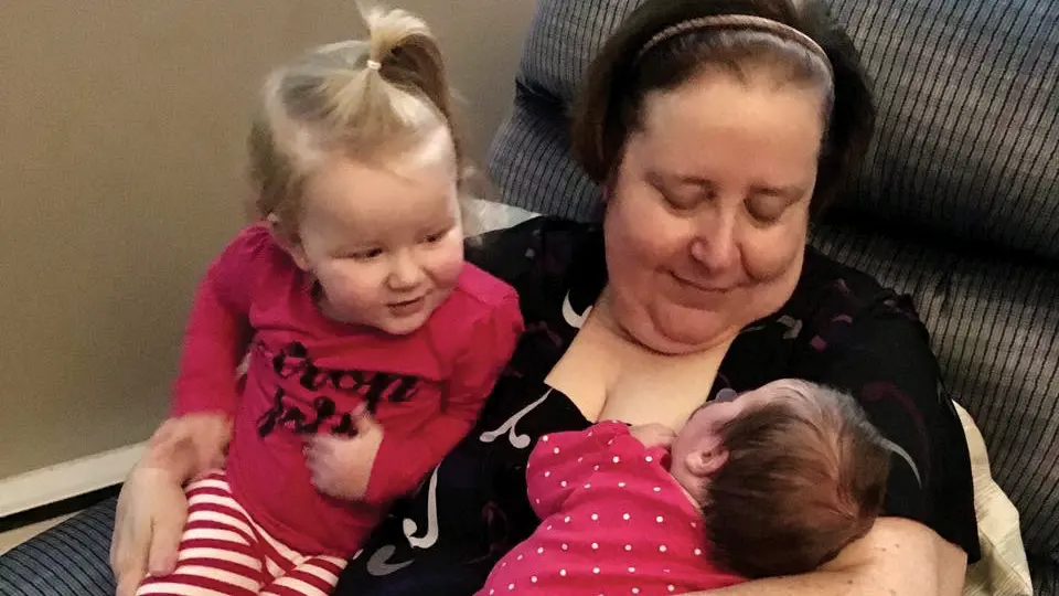 Suzanne Arnold smiles as she holds two young grandchildren.